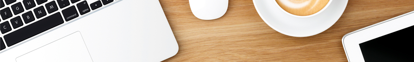 Top down view of desk featuring a laptop, wireless mouse, a tablet and a cappuccino.