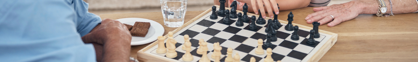 A mature couple playing a game of chess at the kitchen table.