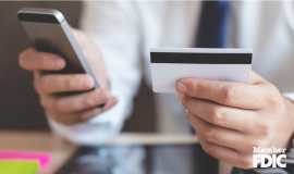 A man holding a cell phone in one hand and a debit card in the other.