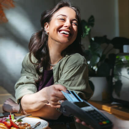 A young woman paying for a meal with a credit card 