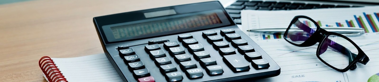 calculator on a desk with a pair of eyeglasses next to it