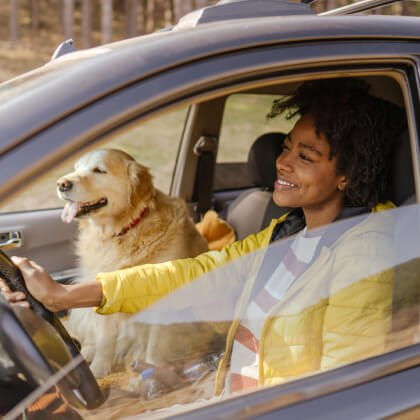 A young woman and dog sitting in a car