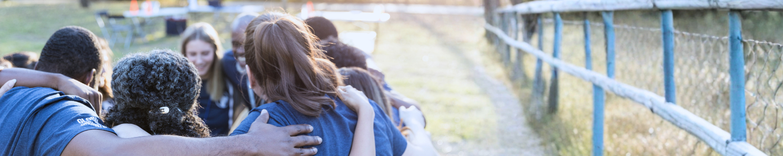 group of people standing in a cicle with their arms around each other
